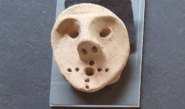 北杜市酒呑場遺跡から出土した土偶の頭部、口のまわりに不気味な穴が十字形に明けられている。